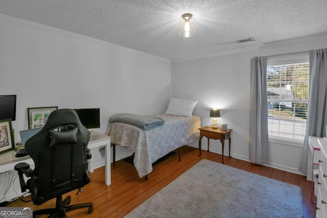 bedroom with hardwood / wood-style floors, a textured ceiling, and ornamental molding