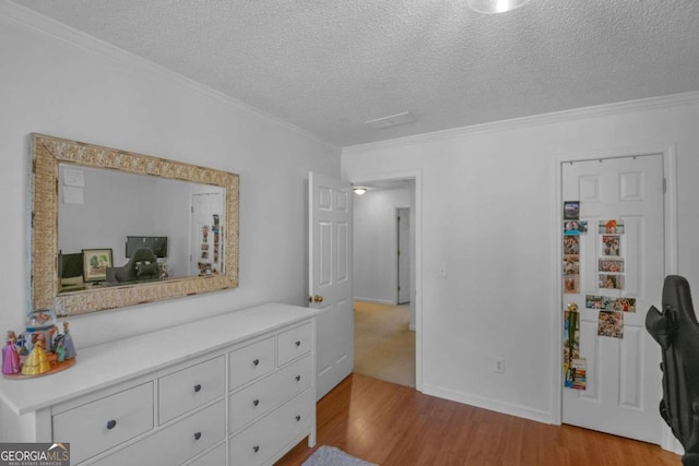 bedroom featuring crown molding, light wood-type flooring, and a textured ceiling