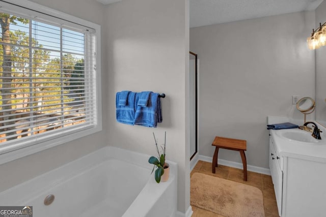 bathroom with tile patterned floors, vanity, a healthy amount of sunlight, and a textured ceiling