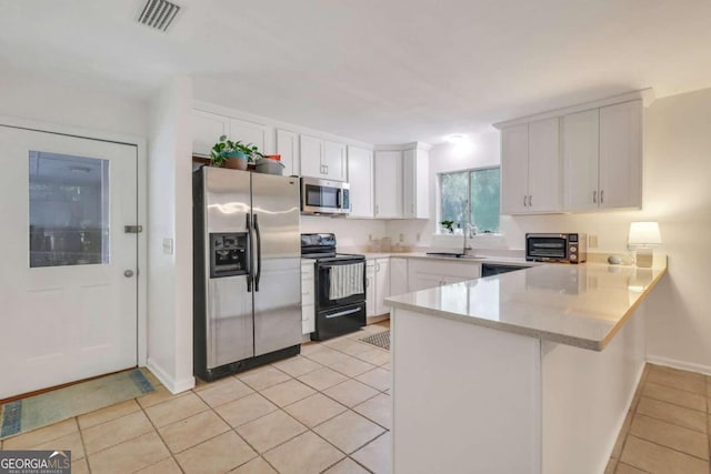 kitchen featuring white cabinets, appliances with stainless steel finishes, light tile patterned floors, and sink