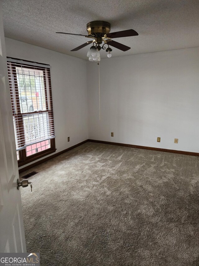 carpeted spare room featuring visible vents, a textured ceiling, and baseboards