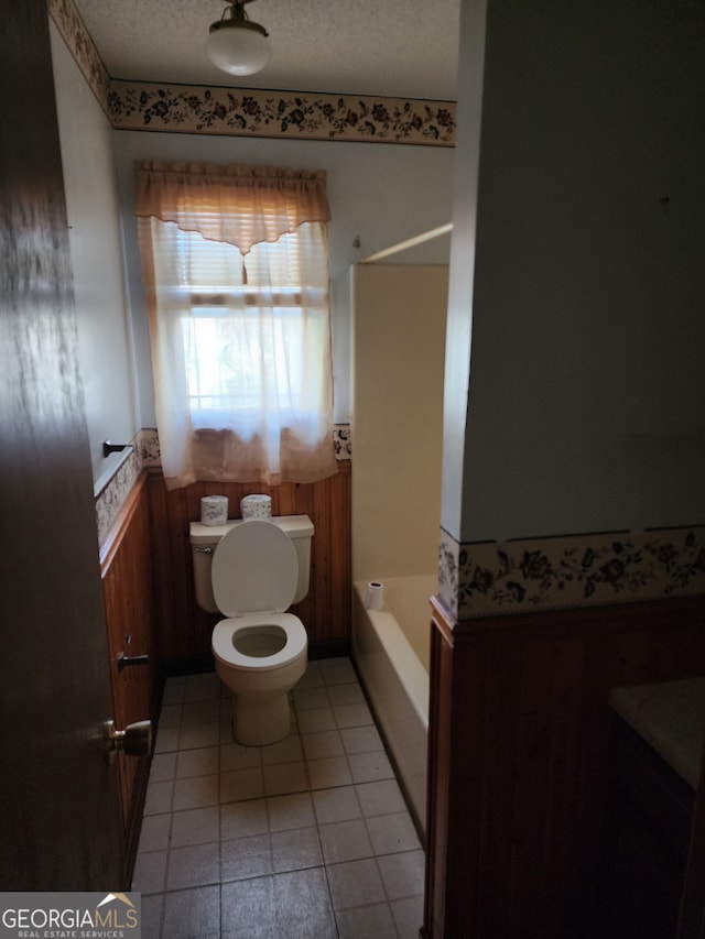 bathroom with tile patterned floors, separate shower and tub, toilet, and a textured ceiling