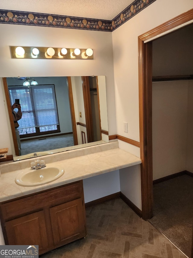 bathroom with vanity, baseboards, and a textured ceiling