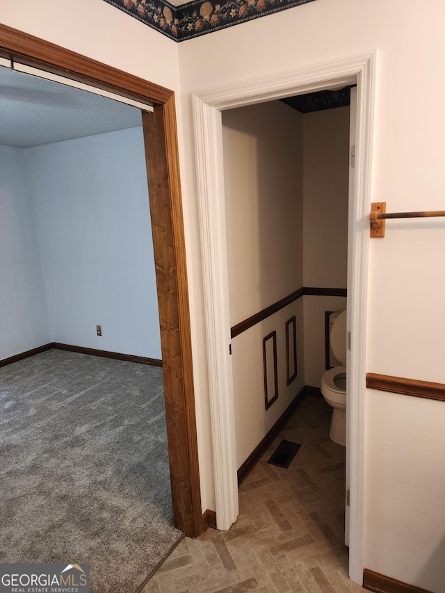 interior space with visible vents, baseboards, and toilet