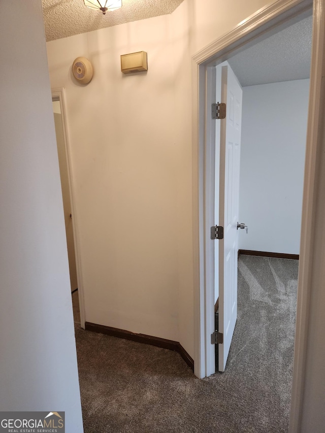 hallway with baseboards, a textured ceiling, and carpet