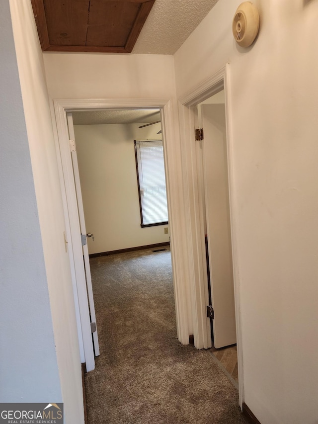 hall featuring baseboards and dark colored carpet