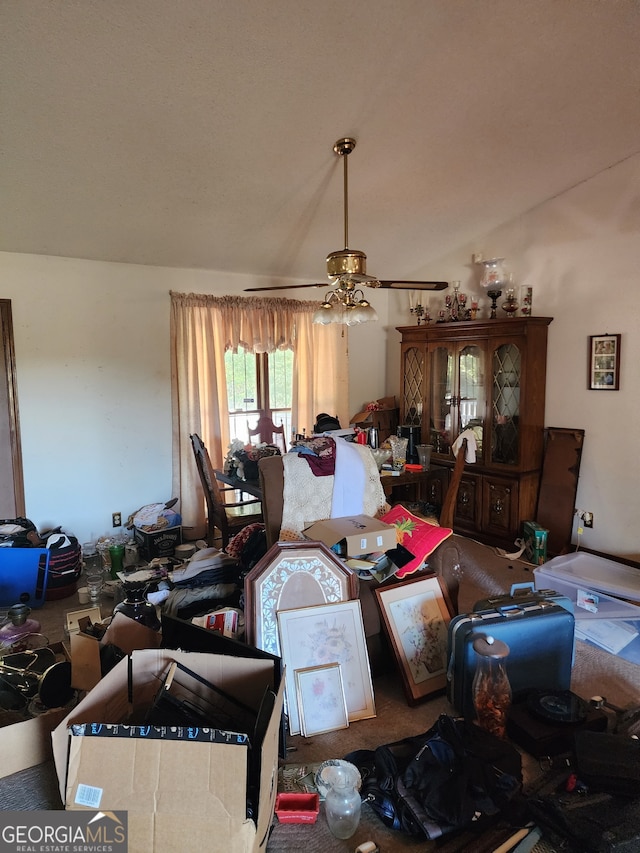 carpeted living room with ceiling fan and vaulted ceiling