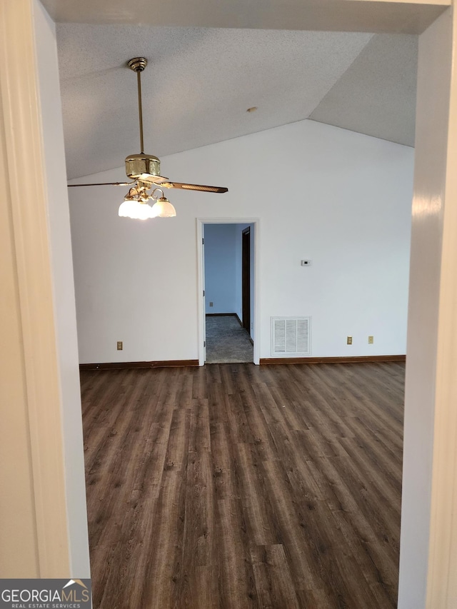 unfurnished room with visible vents, ceiling fan, baseboards, vaulted ceiling, and dark wood-style floors