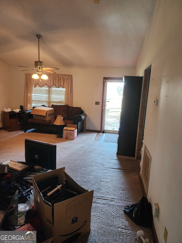 carpeted living room with lofted ceiling, ceiling fan, and a textured ceiling