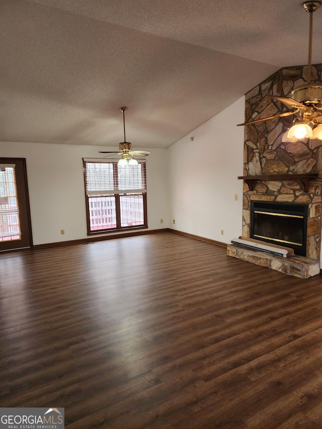 unfurnished living room featuring wood finished floors, ceiling fan, a stone fireplace, vaulted ceiling, and a textured ceiling