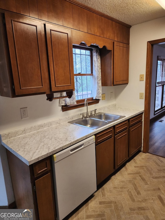 kitchen featuring visible vents, white dishwasher, a sink, light countertops, and a textured ceiling