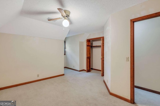 additional living space featuring ceiling fan, light colored carpet, and a textured ceiling