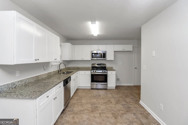 kitchen featuring sink, light stone countertops, a textured ceiling, white cabinetry, and stainless steel appliances