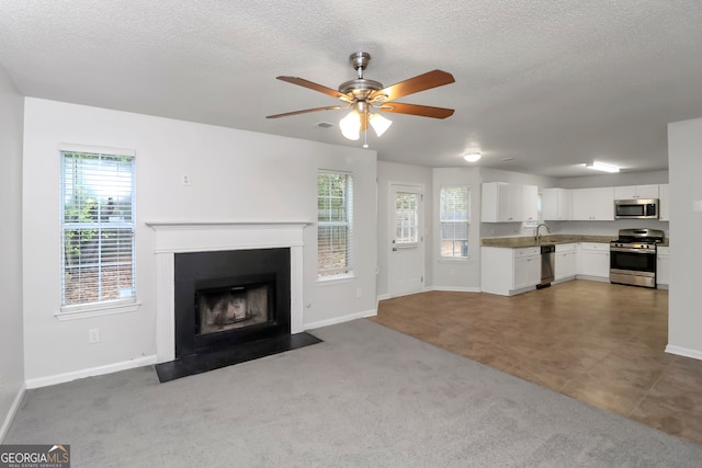 unfurnished living room with plenty of natural light, a textured ceiling, and dark colored carpet