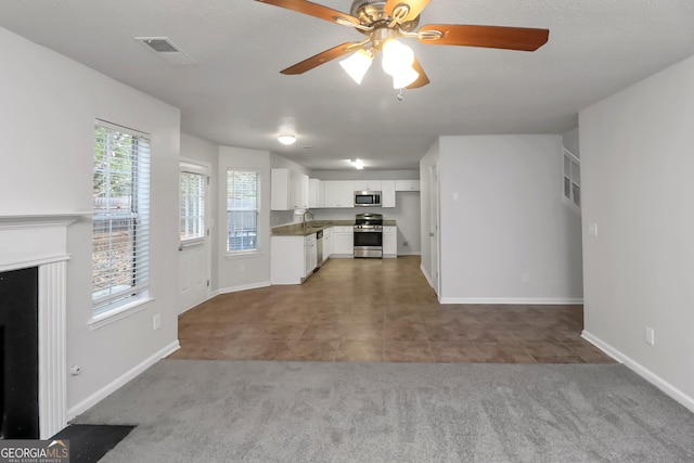 kitchen with white cabinets, ceiling fan, a textured ceiling, appliances with stainless steel finishes, and carpet floors