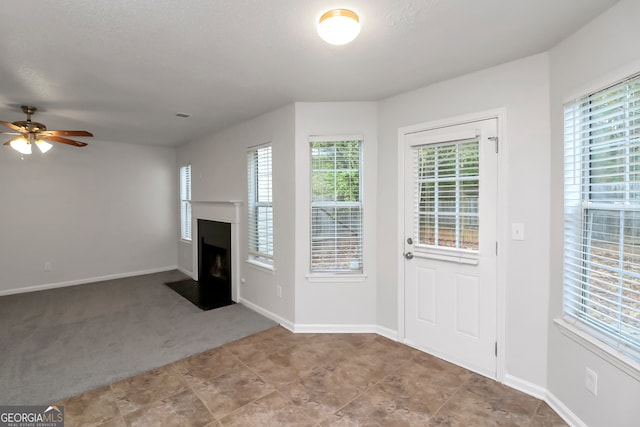 interior space with a textured ceiling, light colored carpet, plenty of natural light, and ceiling fan