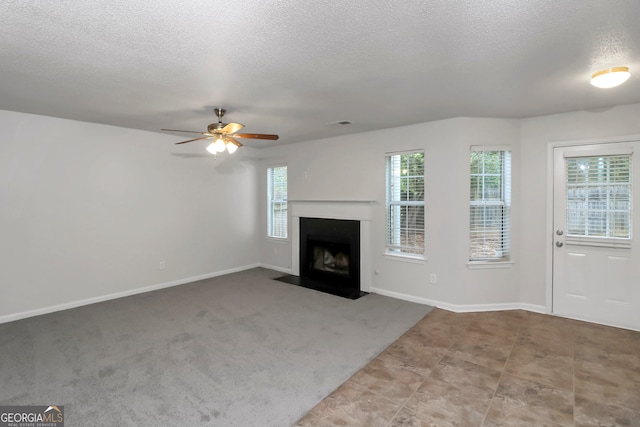 unfurnished living room with ceiling fan, light colored carpet, and a textured ceiling