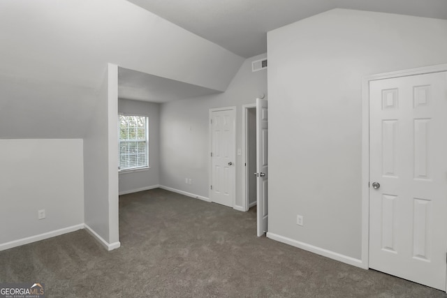 interior space with dark colored carpet and vaulted ceiling