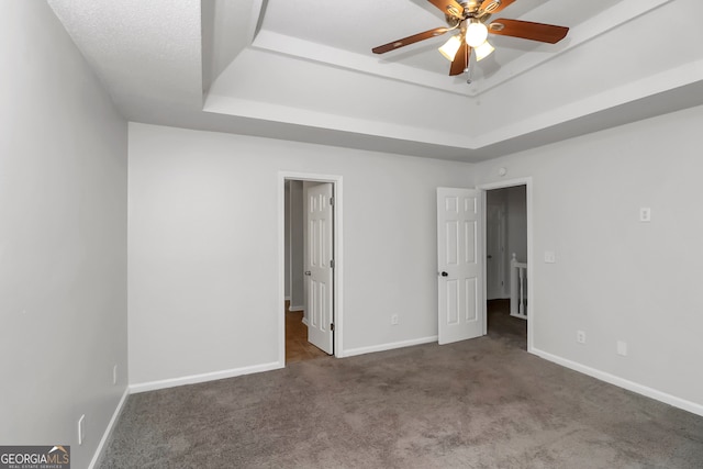 unfurnished bedroom featuring carpet floors, a raised ceiling, and ceiling fan