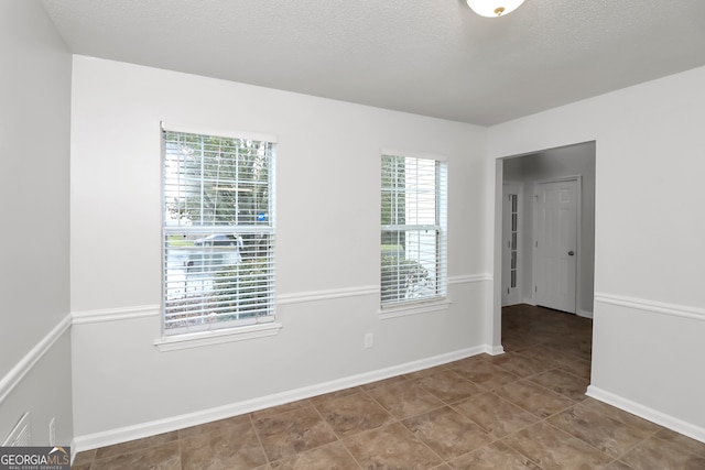 spare room featuring a textured ceiling and a healthy amount of sunlight