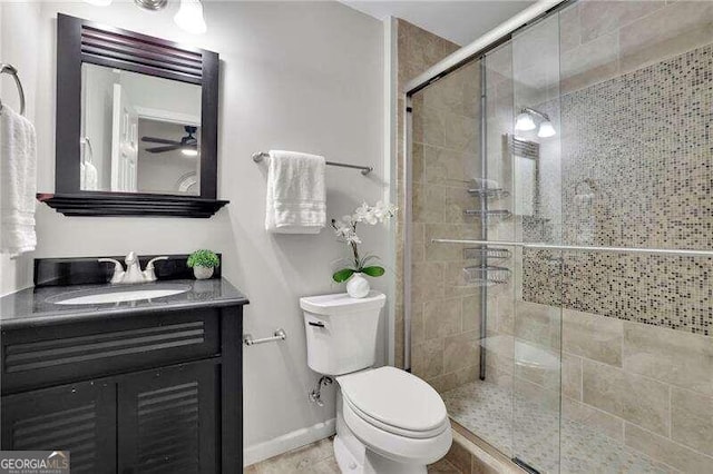 bathroom with ceiling fan, vanity, an enclosed shower, and toilet