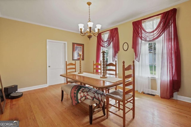 dining room with crown molding, light hardwood / wood-style flooring, and a chandelier