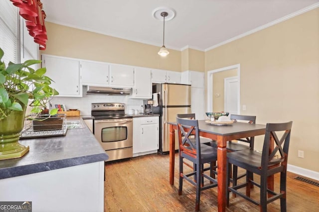 kitchen featuring light hardwood / wood-style floors, decorative light fixtures, white cabinets, exhaust hood, and appliances with stainless steel finishes