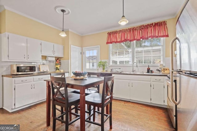 kitchen featuring stainless steel appliances, light hardwood / wood-style flooring, white cabinets, and pendant lighting