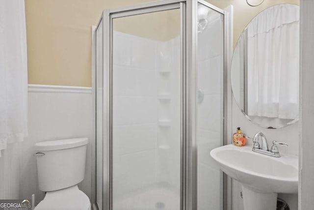 bathroom with toilet, a shower with door, and sink