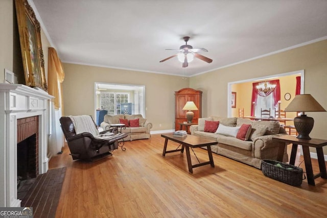 living room with ceiling fan, ornamental molding, a fireplace, and light hardwood / wood-style flooring