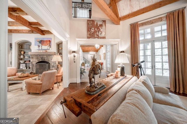 living room featuring beam ceiling, built in shelves, french doors, a fireplace, and hardwood / wood-style flooring