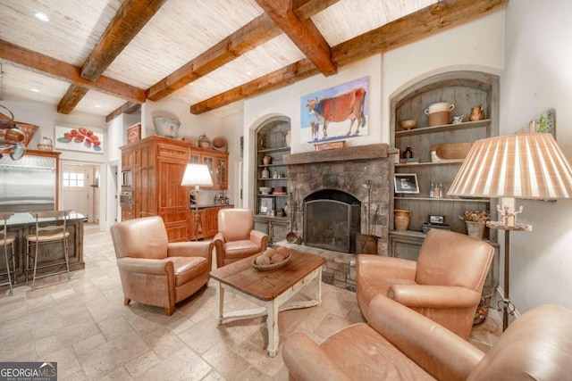 living room featuring built in shelves, a fireplace, beamed ceiling, and wooden ceiling