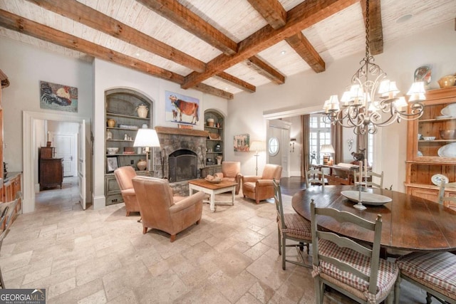 dining area featuring beamed ceiling, built in shelves, a fireplace, and an inviting chandelier