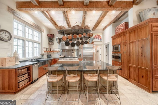 kitchen with wooden ceiling, built in appliances, a large island, beam ceiling, and a breakfast bar area