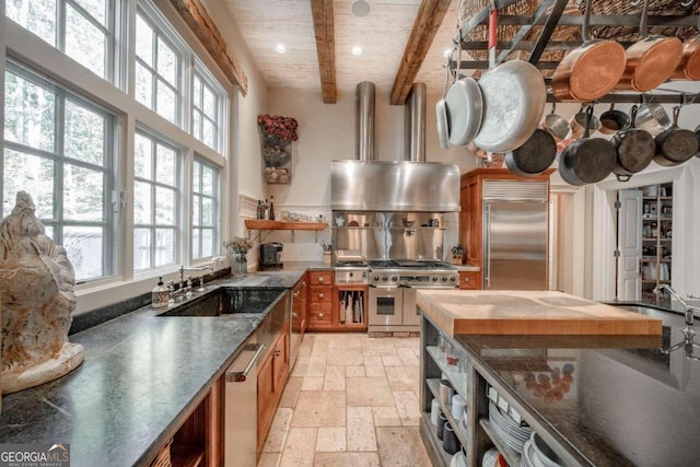 kitchen featuring beamed ceiling, premium appliances, wood counters, and sink