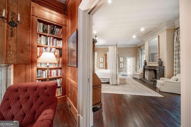 living area featuring crown molding, wood walls, built in features, and dark hardwood / wood-style floors