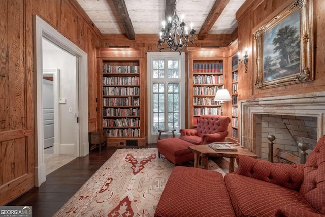 sitting room featuring dark hardwood / wood-style flooring, built in shelves, beam ceiling, an inviting chandelier, and wood walls