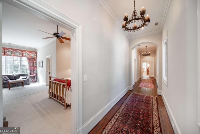 corridor with hardwood / wood-style floors, a notable chandelier, and crown molding