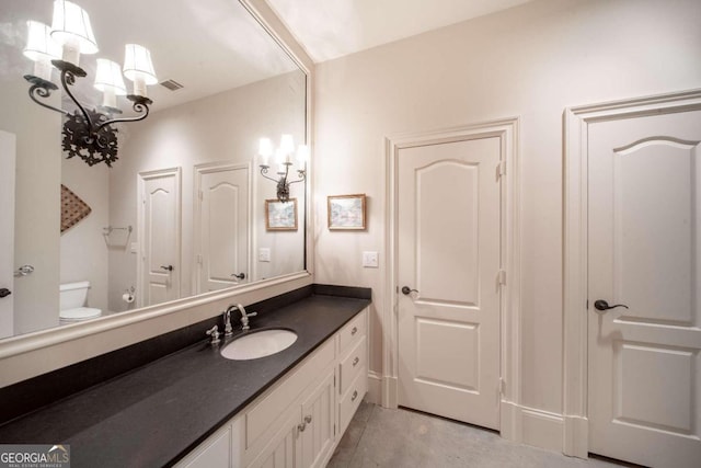 bathroom featuring toilet, vanity, and an inviting chandelier