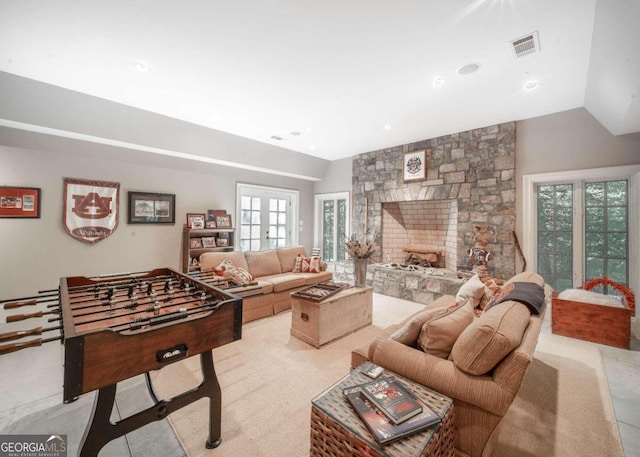 living room featuring french doors, vaulted ceiling, and a stone fireplace