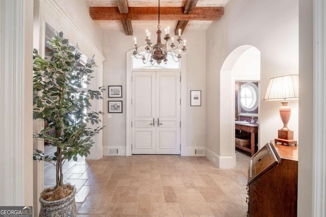 entryway featuring beam ceiling and an inviting chandelier