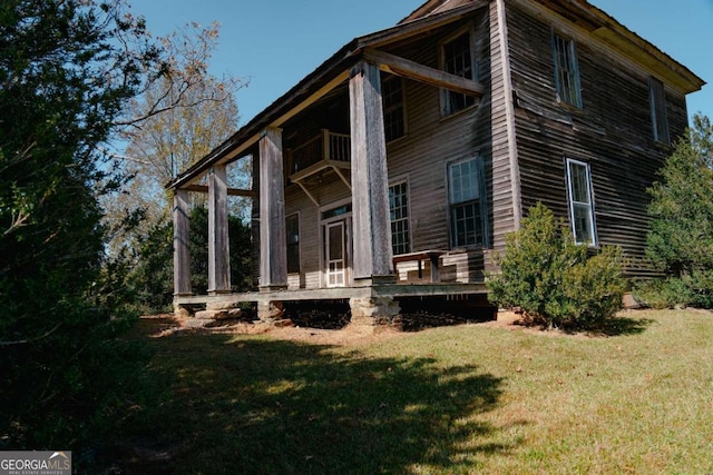 back of house featuring a sunroom, a balcony, and a yard