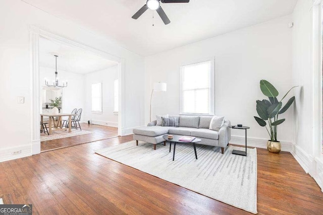 living room featuring dark wood-type flooring and ceiling fan with notable chandelier