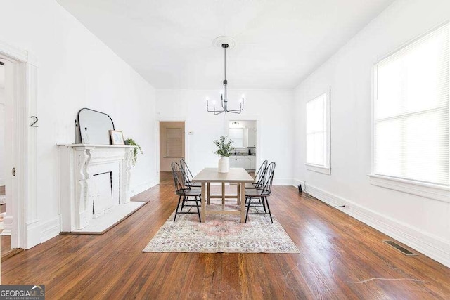 dining room with dark hardwood / wood-style floors and an inviting chandelier