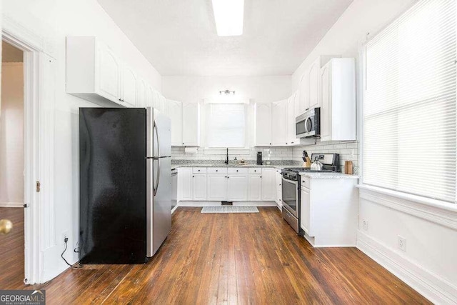 kitchen with tasteful backsplash, dark hardwood / wood-style floors, sink, stainless steel appliances, and white cabinets