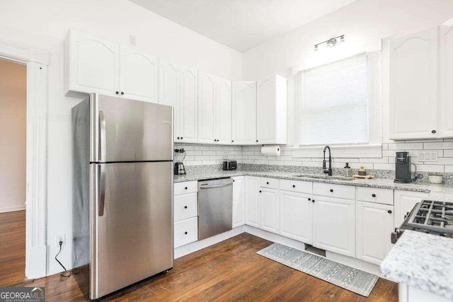 kitchen with appliances with stainless steel finishes, white cabinetry, dark hardwood / wood-style flooring, sink, and light stone counters