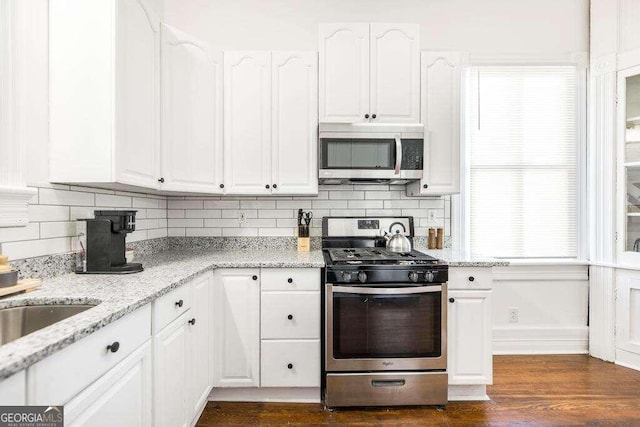 kitchen featuring light stone countertops, white cabinets, stainless steel appliances, and tasteful backsplash