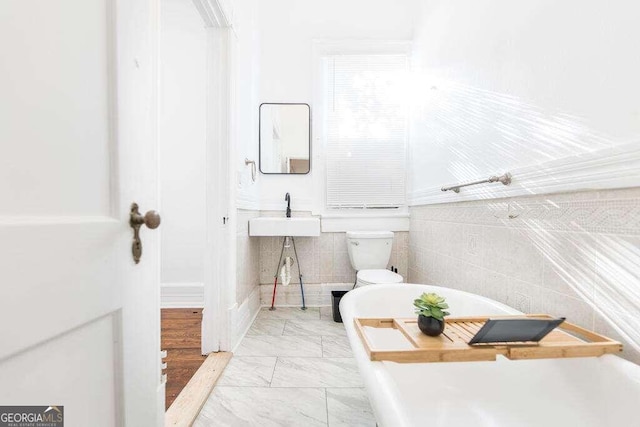 bathroom with toilet, tile walls, and sink