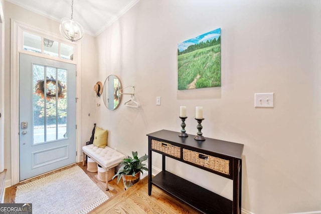 foyer entrance with an inviting chandelier, light hardwood / wood-style flooring, a wealth of natural light, and crown molding