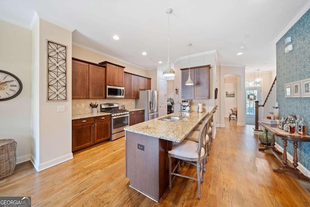 kitchen featuring kitchen peninsula, light wood-type flooring, stainless steel appliances, sink, and a breakfast bar area